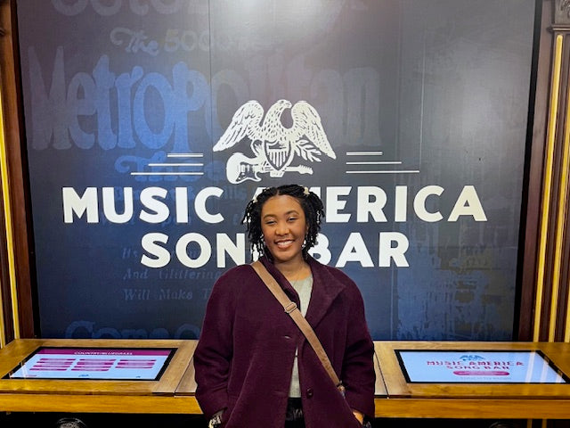 Nahthan is smiling and standing in front of a screen that says music america songbar.